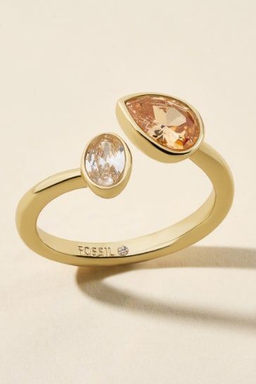 An open gold-tone ring featuring a clear round crystal on one end and an amber pear-shaped stone on the other.