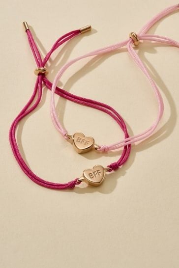 A pair of women's corded bracelets in light pink and dark pink featuring a gold-tone heart engraved with BFF.