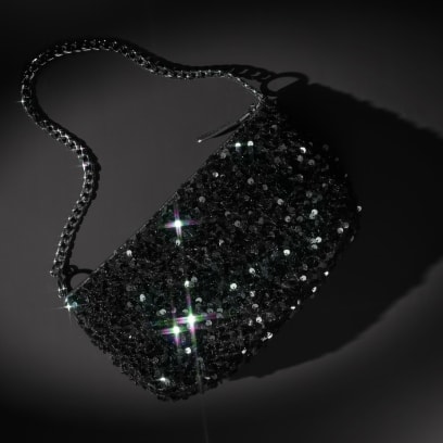 Une pochette noire à paillettes avec un bracelet chaîne noir.