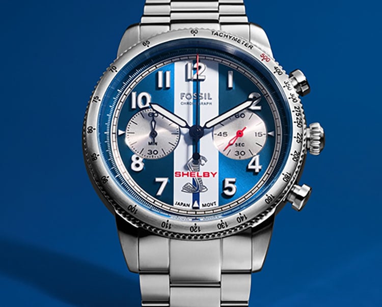 A heroic shot of the Shelby and Fossil Grand Tourer limited-edition chronograph, featuring a stainless steel case and blue-and-white striped dial inspired by iconic Shelby racing vehicles.