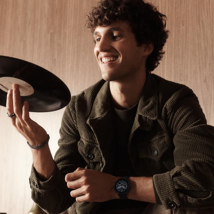A man spinning a vinyl record while wearing a Gen 6 Hybrid smartwatch.