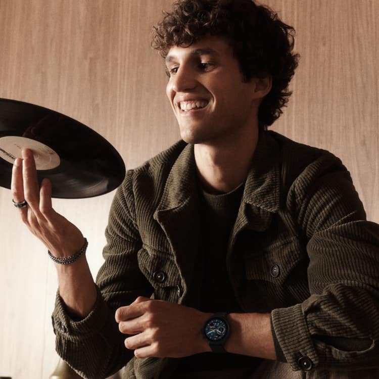 A man spinning a vinyl record while wearing a Gen 6 Hybrid smartwatch.