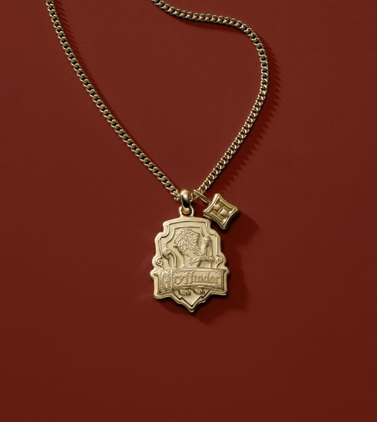Gold-tone Gryffindor house watch with a red and gold strap and a gold-tone Gryffindor house pendant.
