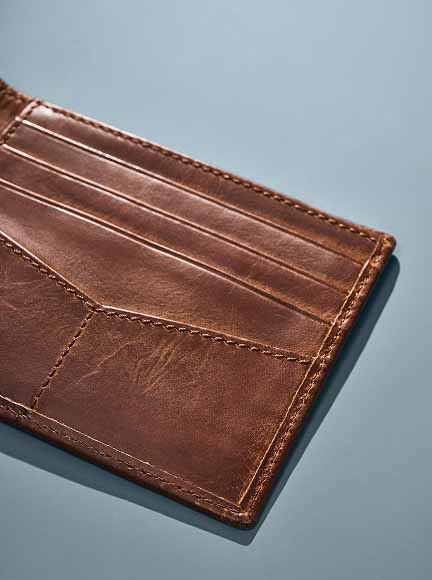 A Fossil wallet, shown in rich brown leather, embossed with the initials JHE.