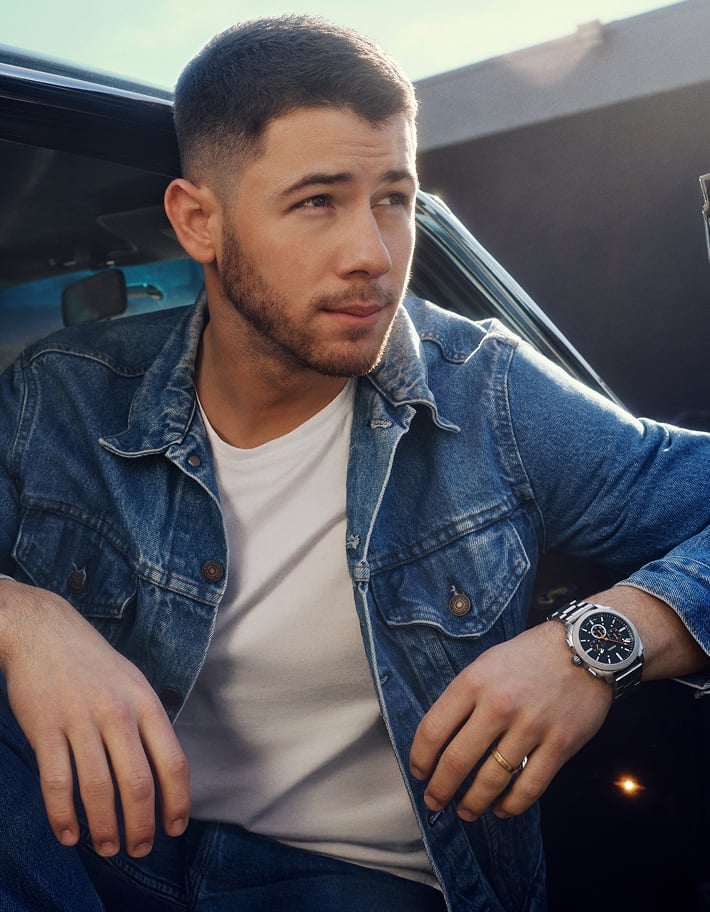 Singer, songwriter and actor Nick Jonas, pictured in a denim jacket and white tee, wearing a limited-edition Machine luxe watch from his exclusive collaboration with Fossil.