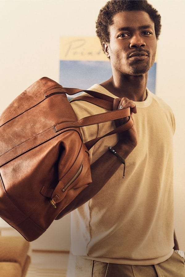 A man carrying the brown leather Raeford duffle over his shoulder.