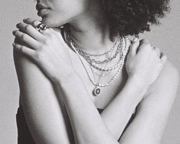 Imagen en blanco y negro de una mujer con una combinación de collares.