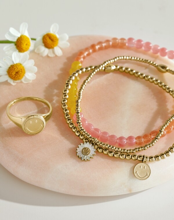 Gold-tone and beaded Fossil x Smiley jewelry styles.