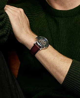 Ein Mann in einem blauen Strickpullover, der eine Uhr Townsman mit einem Zifferblatt mit blauem Finish und einem braunen Lederband trägt.