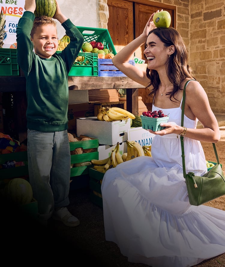 A mom and son being playful at a fruit market.