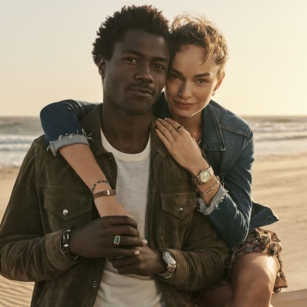 A man and a woman embracing and smiling while wearing pieces from the Fossil Heritage Collection.