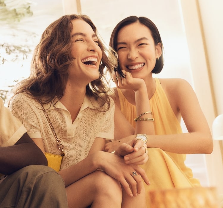 Four pairs of stud earrings sit on a table: a pair of blue heart crystals with yellow enamel edging, a pair of pink heart crystals with pink enamel edging, a pair of snake studs with green and yellow enamel, a pair of pink enamel mushroom studs with gold-tone stainless steel and crystal embellishments.
