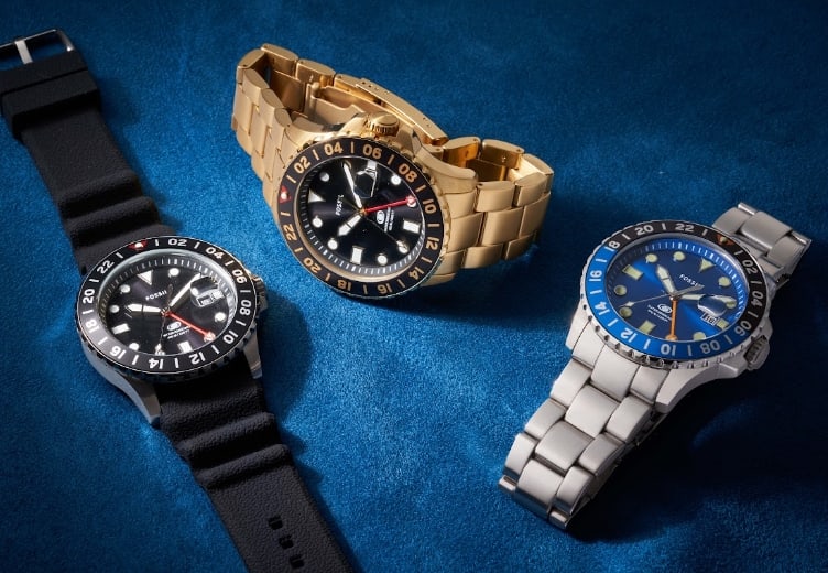 Un reloj GMT Blue de Fossil en color negro, un reloj GMT Blue de Fossil en tono dorado y un reloj GMT Blue de Fossil en tono plateado.