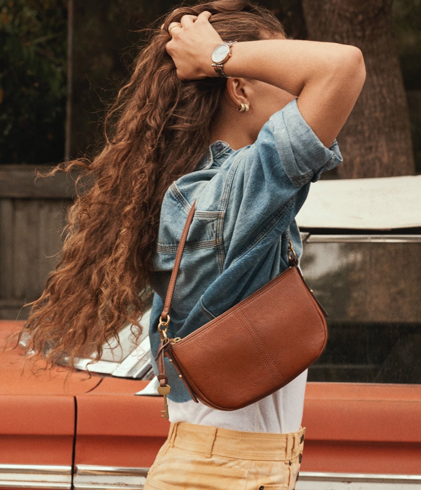 Jolie Baguette. A woman wearing a brown leather bag and an image of a brown leather bag open with arrows pointing to its contents. 