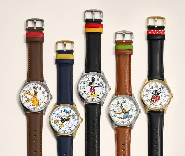 Ein Gruppenbild der fünf Uhren von Micky und seinen Freund*innen neben dem D100-Logo zur Feier von Disneys 100. Jubiläum.