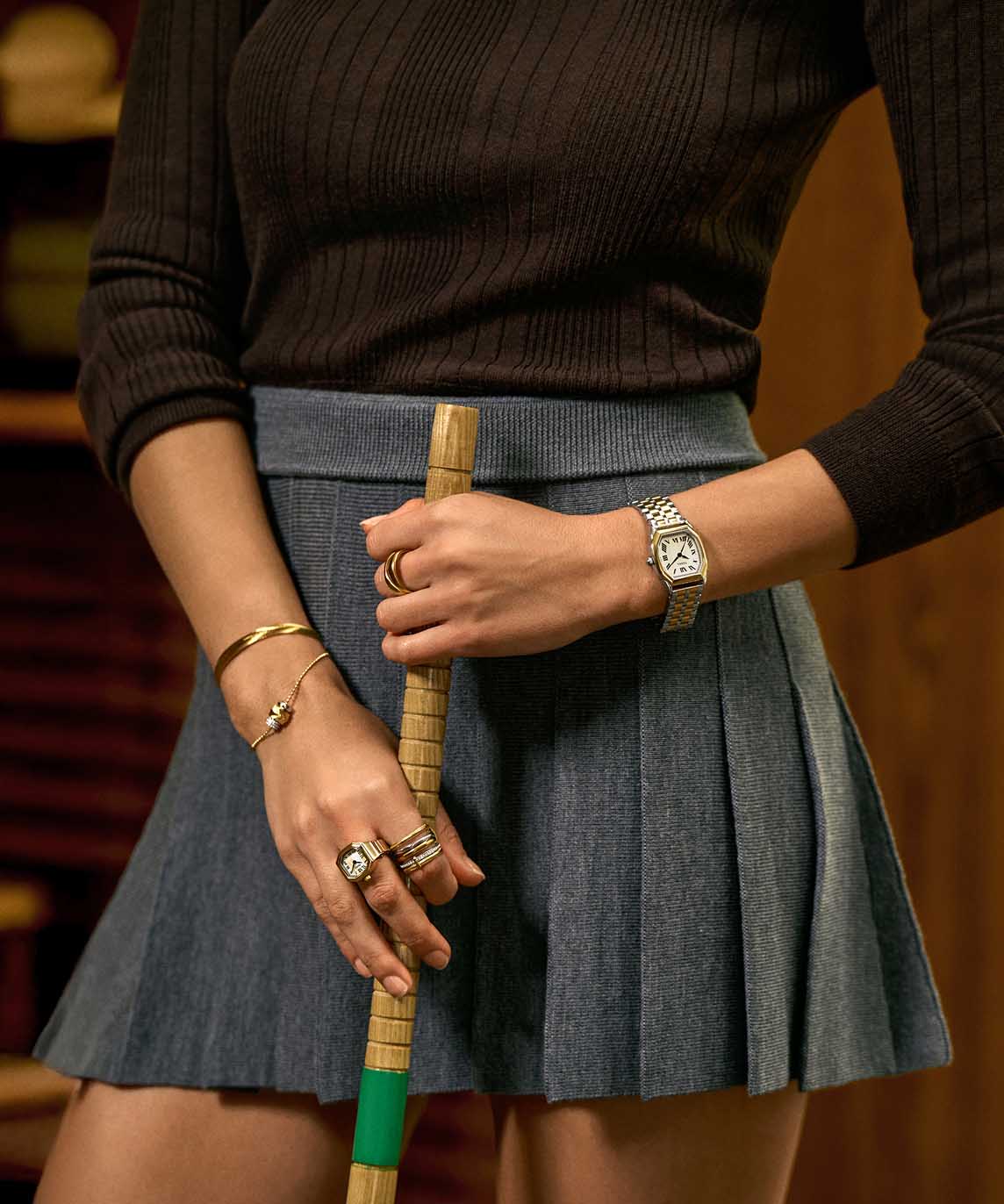 A tight crop of a woman's waist featuring her hands and arms decorated with multiple Fossil watches and jewelry.