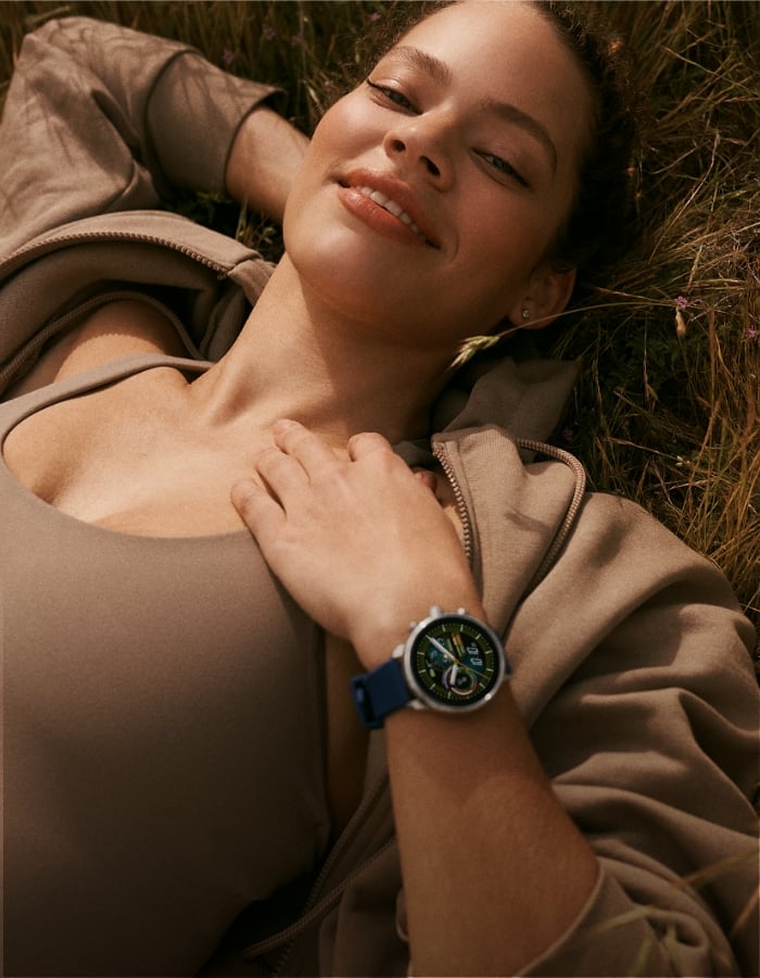 A woman in a yoga position wearing a Gen 6 Wellness Edition smartwatch.