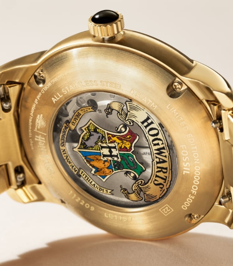 Reloj automático Harry Potter™ en tono dorado que muestra un escudo de Hogwarts™ oculto en la parte posterior de la caja.