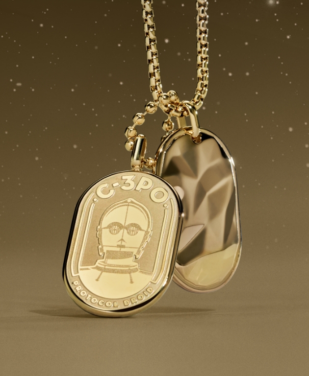 A gold-tone necklace with an engraving of C-3PO on an ID plaque