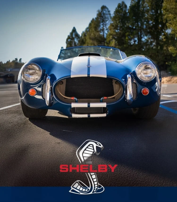 The blue and white striped Shelby Grand Tourer chronograph watch shown side by side with a classic Shelby sports car in the same bold colorway, along with the Shelby Cobra logo.
