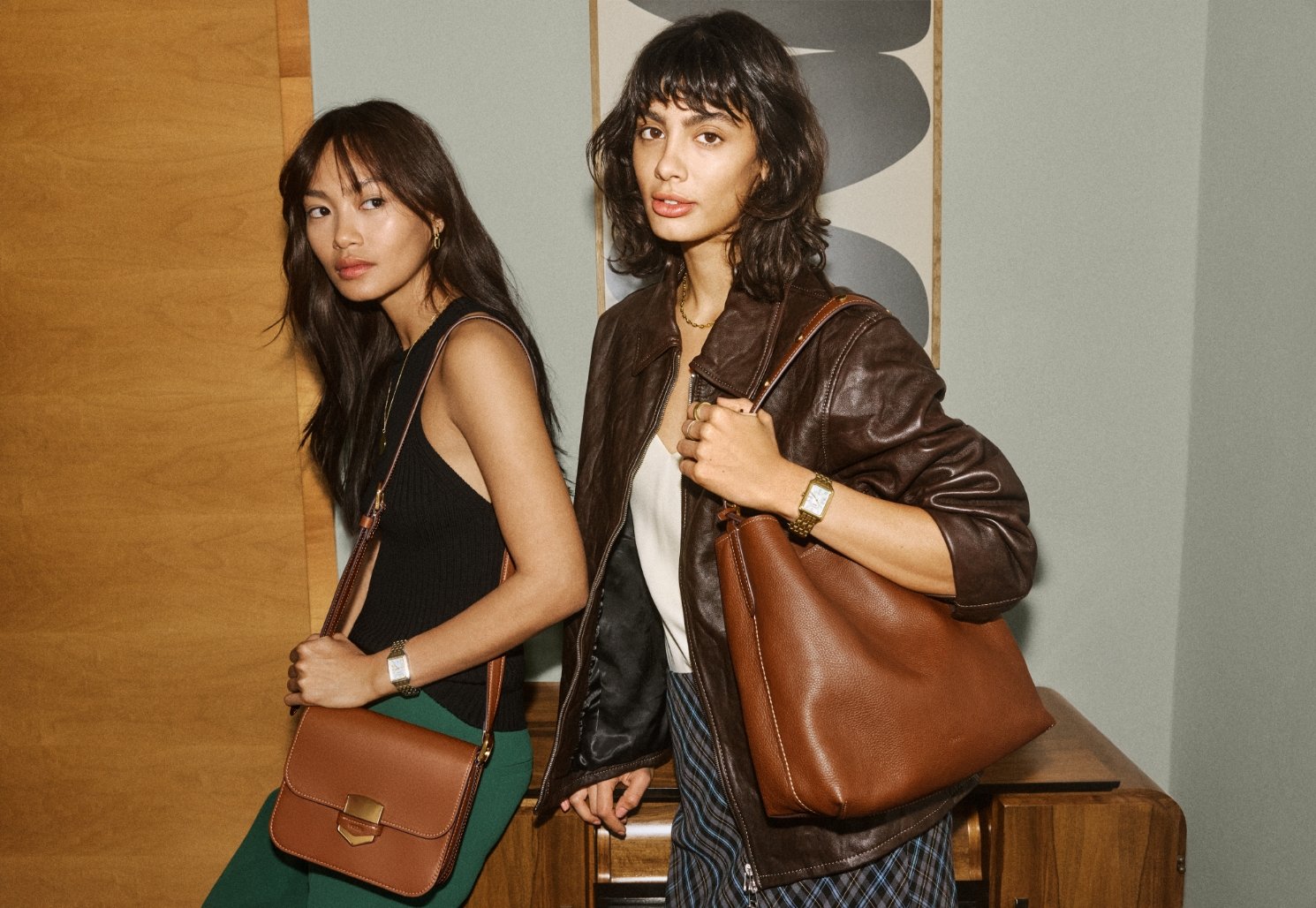 Two women carrying the brown leather Lennox handbag and the brown leather Jessie Bucket bag.