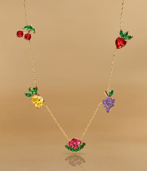 A gold-tone chain featuring five fruit-shaped crystal accents.