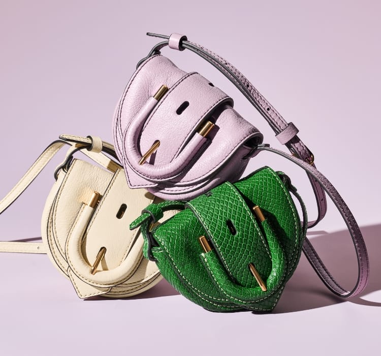 Three micro bags in light purple, python-embossed green and ivory (clockwise from the top) and a woman sitting on a skateboard wearing the python-embossed green and ivory micro crossbody bags.