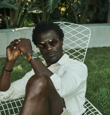 Man wearing brown sunglasses and leather watch.