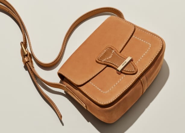 Una GIF con una borsa Tremont in pelle scamosciata marrone, con in primo piano l’imbastitura a tre colori e i bordi grezzi.