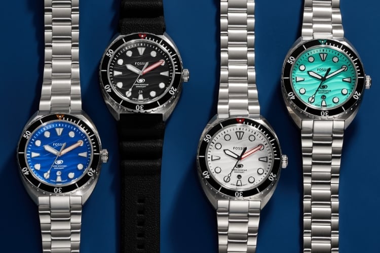 Quatre montres Fossil Breaker : une avec un bracelet argenté et un cadran bleu, une avec un bracelet en silicone noir et un cadran noir, une avec un bracelet argenté et un cadran blanc, et une avec un bracelet argenté et un cadran bleu sarcelle.