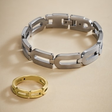 Un bracciale color argento e un anello color oro.