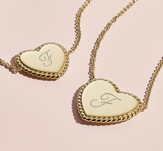 Two gold-tone, heart-shaped pendant necklaces engraved with an X and an O.