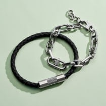 Two men's bracelets: one black leather with a textured metal accent and one D-link chain.