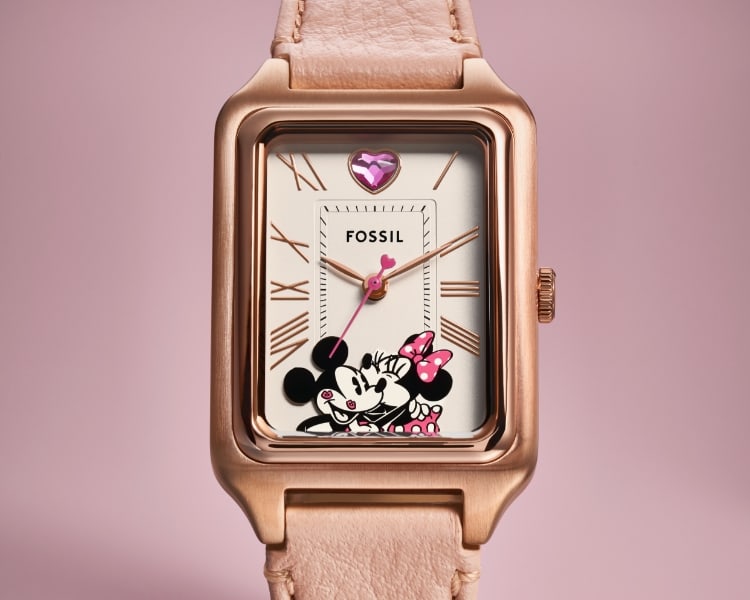 Die Uhr Disney Mickey Mouse & Minnie Mouse mit roséfarbenem Lederband und Micky und Minnie Maus auf dem Zifferblatt. Auf 12 Uhr befindet sich ein rosafarbener, herzförmiger Glasstein.
