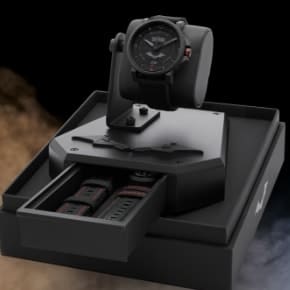 The black Batman x Fossil watch set atop a black display base.
