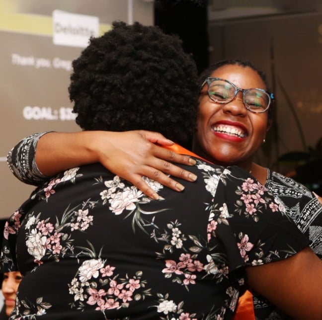 Deux femmes s’étreignent et se sourient.