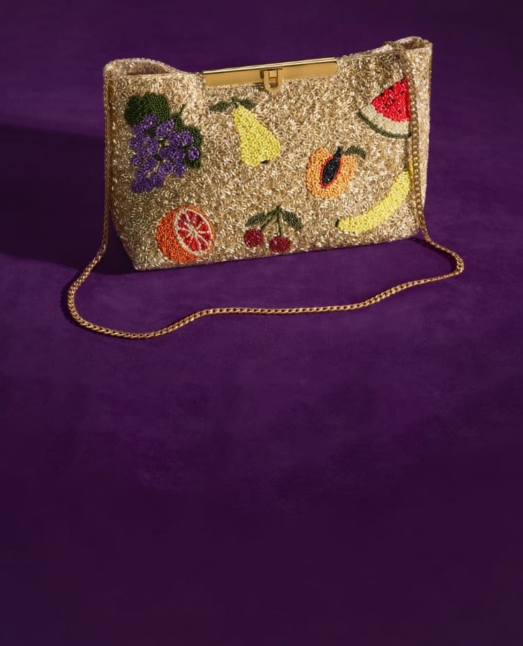 Una clutch con perline a forma di frutta applicate a mano, ispirata alla carta da parati leccabile di Willy Wonka. 