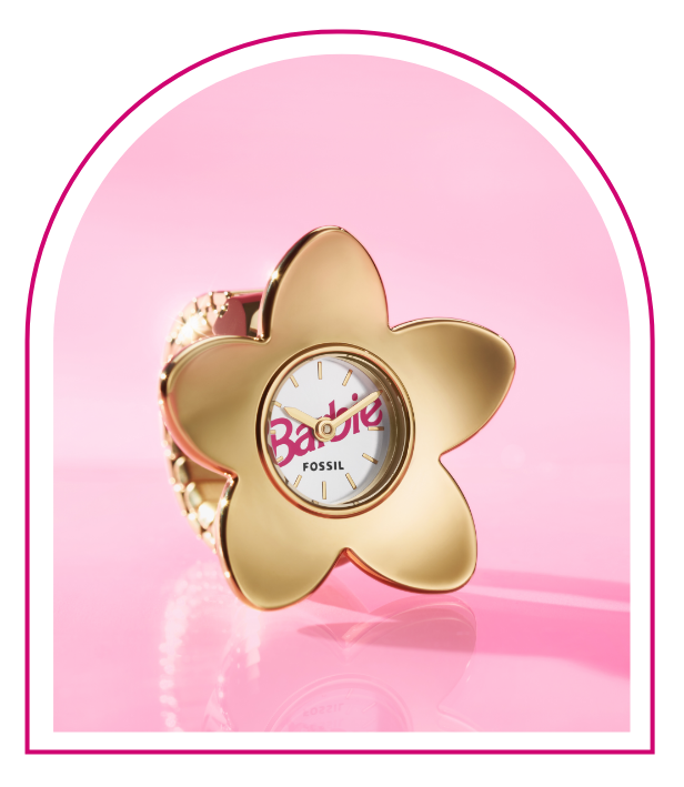 A pink background with a Barbie™ Mansion-inspired window. Inside the window sits our limited-edition Barbie™ x Fossil watch ring, featuring a gold-tone five-petal flower design, white dial with pink barbie logo and flexible band to fit any finger.