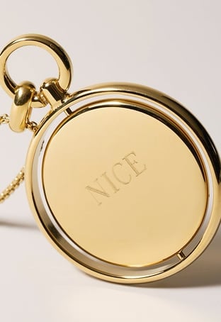 A gold-tone pendant necklace spins to reveal an engraving on each side: naughty and nice.