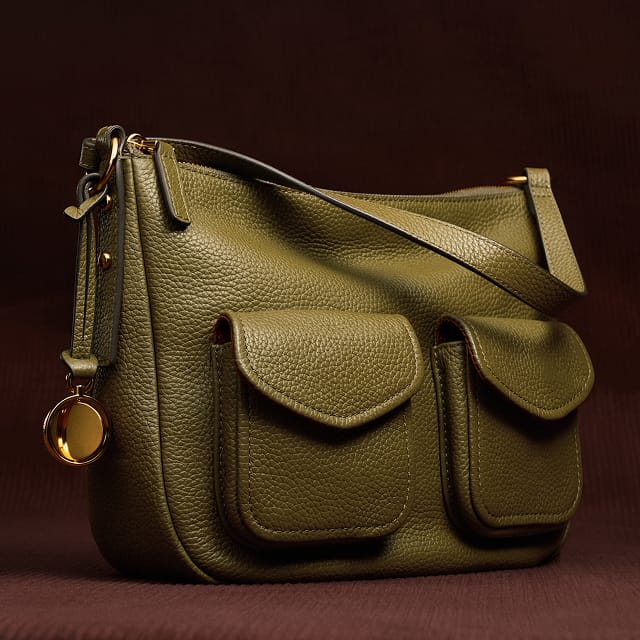 An olive green leather shoulder bag with two front utility pockets.
