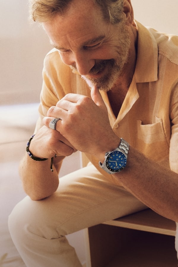 A man smiling and wearing the silver-tone Fossil Blue GMT with a blue dial.