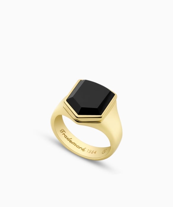 Une chevalière dorée avec une pierre en onyx noir.