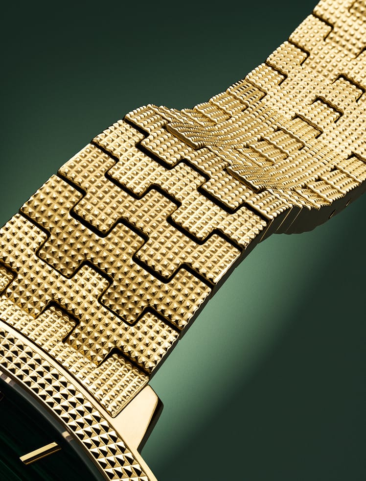 A close-up of the watch on a green checkerboard backdrop.