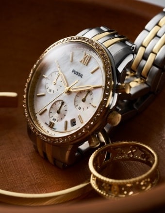 Fossil watch surrounded by gold Fossil jewelry.