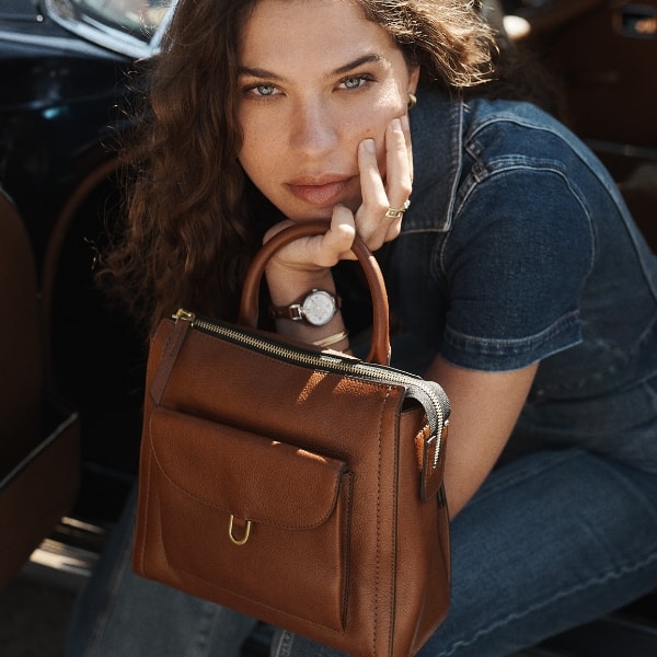 A woman holding the brown leather Parker Mini backpack.