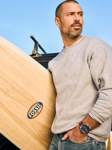 A side-by-side view of a man carrying a surfboard while wearing the Fossil Townsman Automatic, shown alongside a detailed image of the same watch.