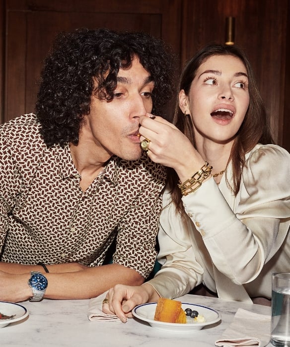 Un homme et une femme mangeant du gâteau et portant les modèles de la collection Automne 2023. 
