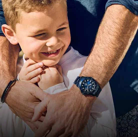 A father wearing the Fossil Blue watch, wrapping his arms around his smiling son.