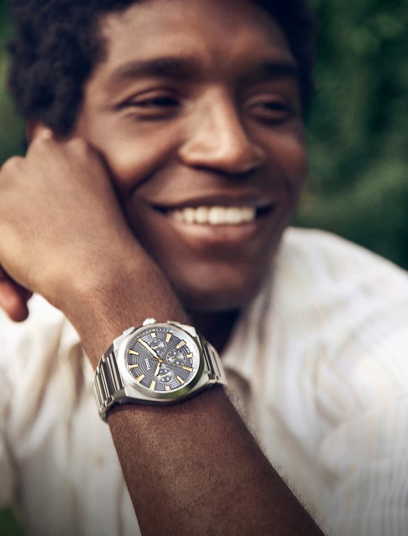 A side-by-side view of a woman and a man in a spring meadow setting wearing Fossil watches