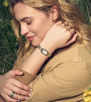 A woman wearing the watch, looking down and smiling.
